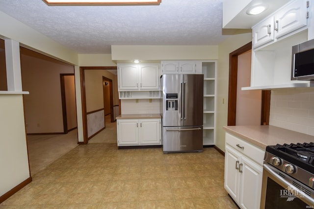 4105 W Friar Dr, Muncie, IN 47304 - kitchen with stainless steel appliances, light countertops, white cabinetry, decorative backsplash, and a textured ceiling