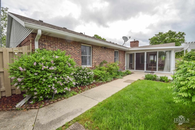 4105 W Friar Dr, Muncie, IN 47304 - back of property with brick siding, a sunroom, a chimney, and a yard