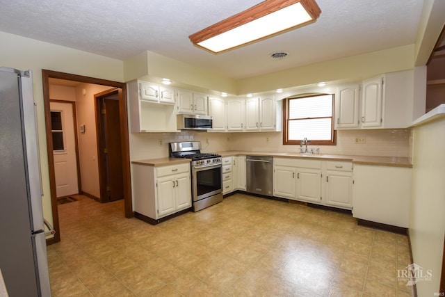 4105 W Friar Dr, Muncie, IN 47304 - kitchen with stainless steel appliances, white cabinets, a sink, and a textured ceiling