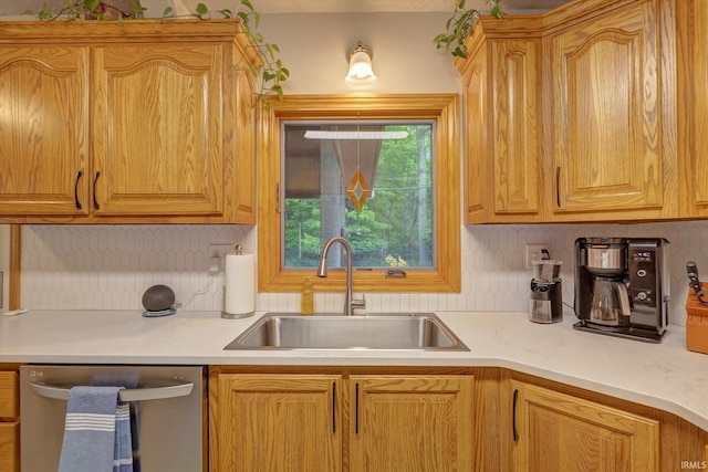 kitchen featuring dishwasher, a sink, tasteful backsplash, and light countertops
