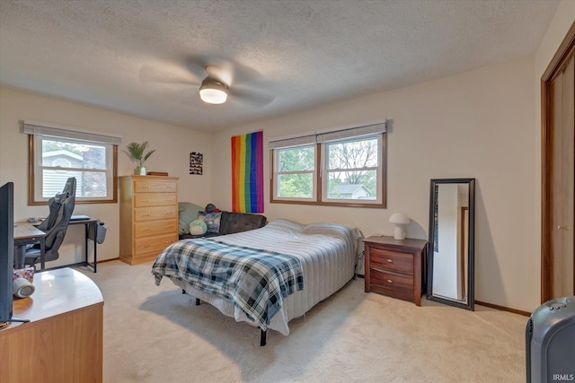 bedroom featuring light carpet, ceiling fan, a textured ceiling, and baseboards