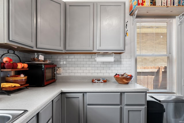 1134 N 14th St, Lafayette, IN 47904 - kitchen with gray cabinets, backsplash, light countertops, and black microwave