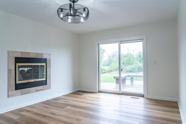 2375 N 110 W, Angola, IN 46703 - unfurnished living room with wood finished floors, baseboards, a chandelier, and a tiled fireplace
