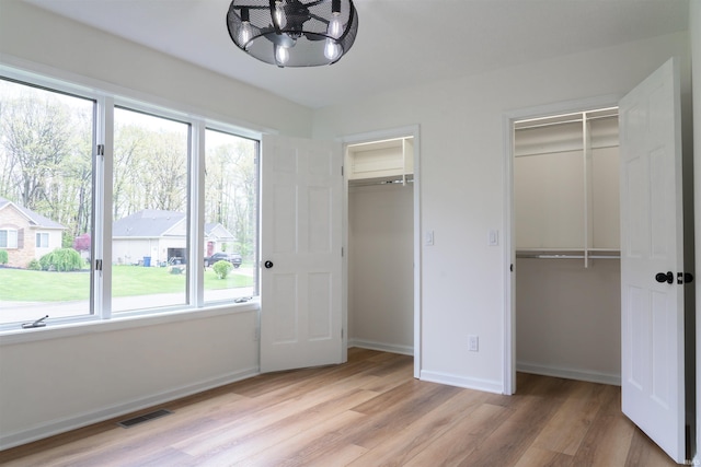 2375 N 110 W, Angola, IN 46703 - unfurnished bedroom with two closets, multiple windows, light wood-style floors, and a chandelier