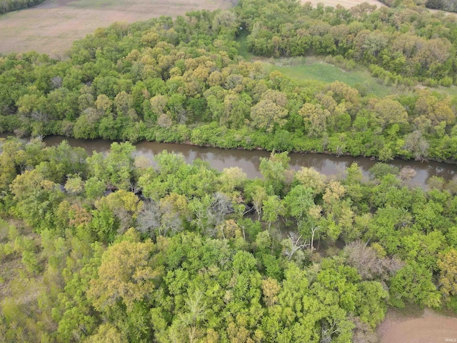 aerial overview of property's location with a nearby body of water and a heavily wooded area