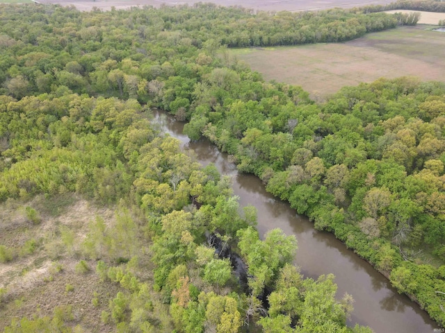 drone / aerial view of a nearby body of water and a heavily wooded area