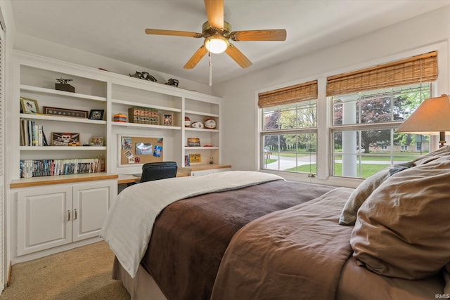 bedroom with multiple windows, light carpet, an office area, and ceiling fan