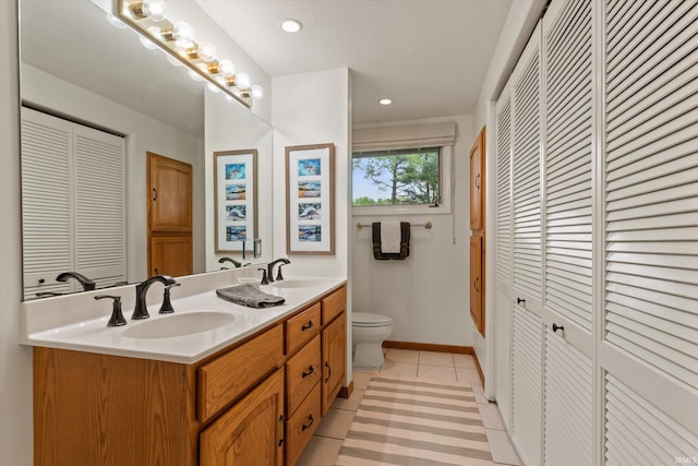 full bathroom featuring a closet, toilet, double vanity, tile patterned flooring, and baseboards