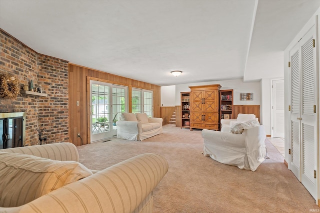 carpeted living room featuring wooden walls, a brick fireplace, and wainscoting