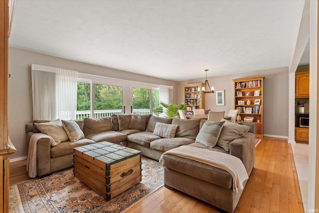 living room featuring a chandelier, light wood-style flooring, and baseboards