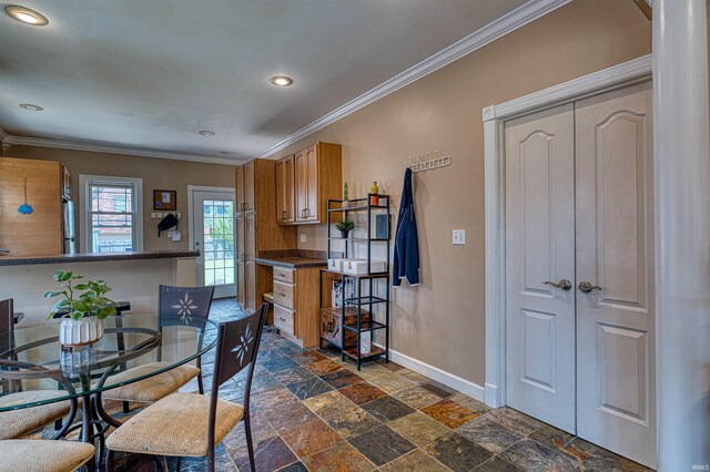 1908 E Mulberry St, Evansville, IN 47714 - kitchen with stone tile flooring, baseboards, ornamental molding, dark countertops, and brown cabinets