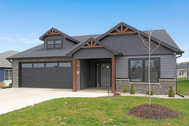 craftsman-style home featuring stone siding, a front yard, concrete driveway, an attached garage, and roof with shingles