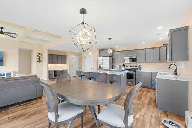 dining space featuring light wood-type flooring, beam ceiling, recessed lighting, ceiling fan, and a chandelier