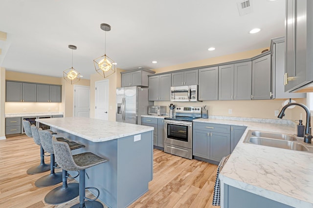 kitchen with stainless steel appliances, a sink, a breakfast bar, a center island, and light wood-type flooring