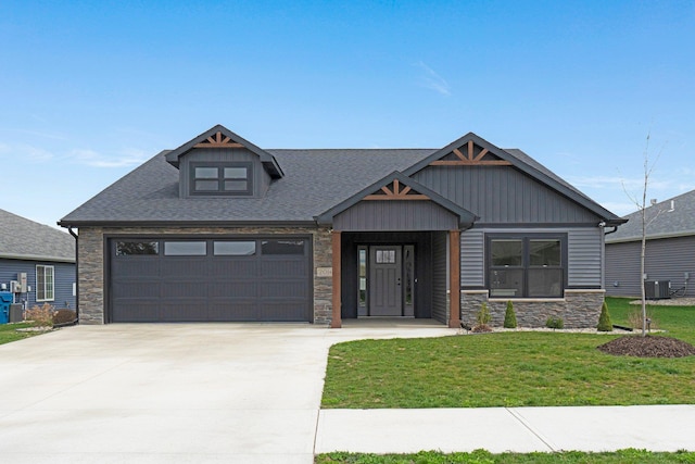 craftsman house featuring stone siding, a front yard, driveway, central AC, and a garage