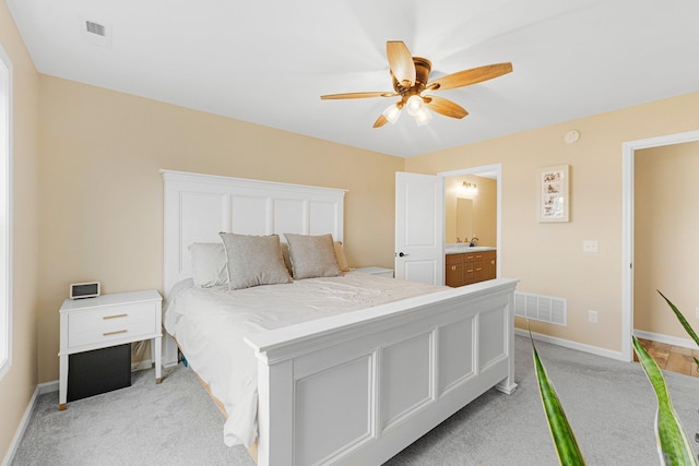 bedroom with light carpet, baseboards, ceiling fan, and ensuite bathroom