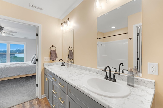 ensuite bathroom with wood finished floors, double vanity, ceiling fan, and a shower