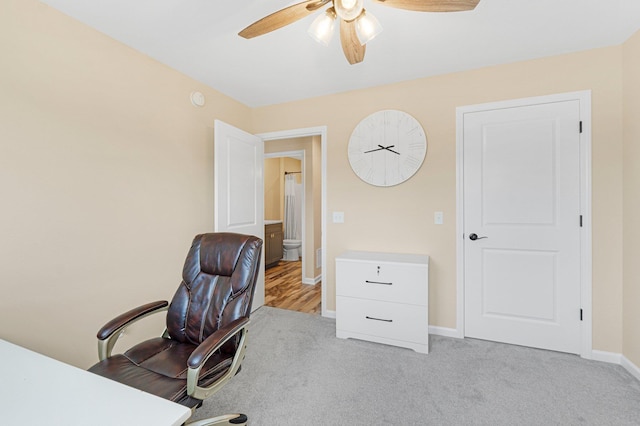 office area featuring a ceiling fan, baseboards, and light carpet