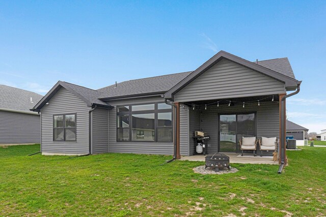 rear view of house featuring a lawn, a patio, roof with shingles, and central AC