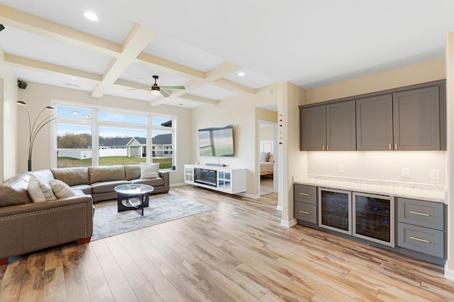 living area with a bar, light wood-style flooring, ceiling fan, coffered ceiling, and beamed ceiling