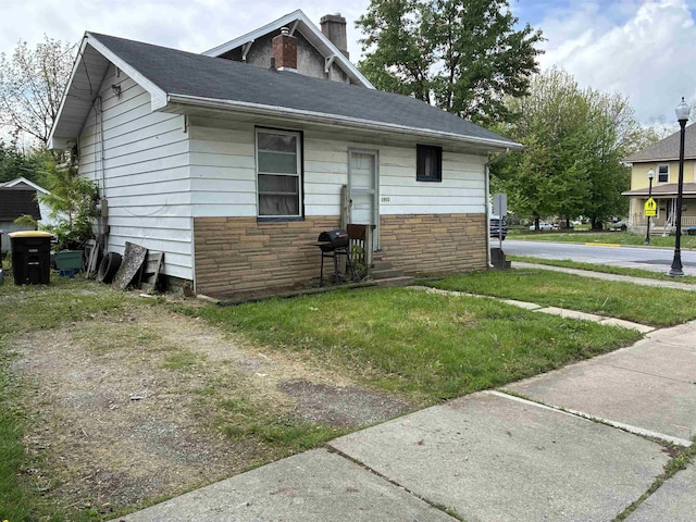 view of front of home featuring a chimney, stone siding, and a front lawn