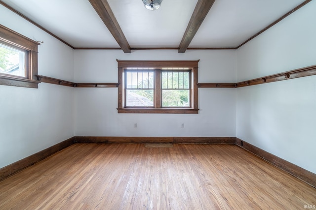 spare room featuring wood finished floors, beamed ceiling, and baseboards