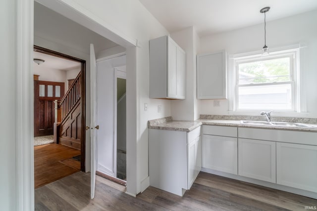 kitchen featuring a sink, wood finished floors, light countertops, and decorative light fixtures