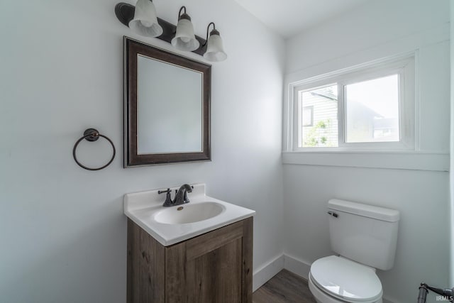 bathroom featuring vanity, toilet, wood finished floors, and baseboards