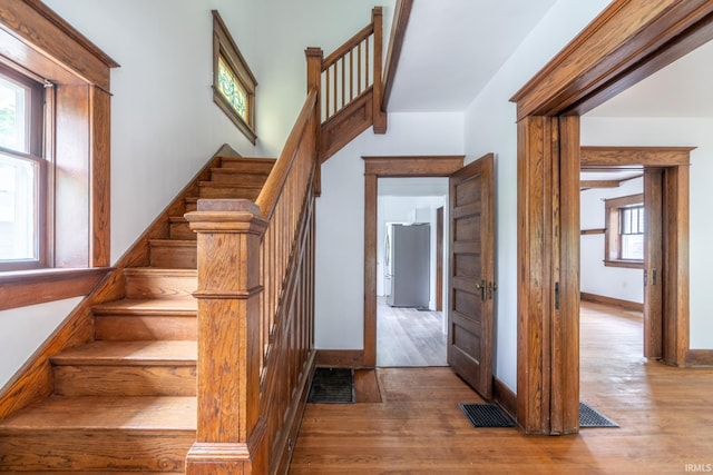 stairs featuring wood finished floors, plenty of natural light, and baseboards