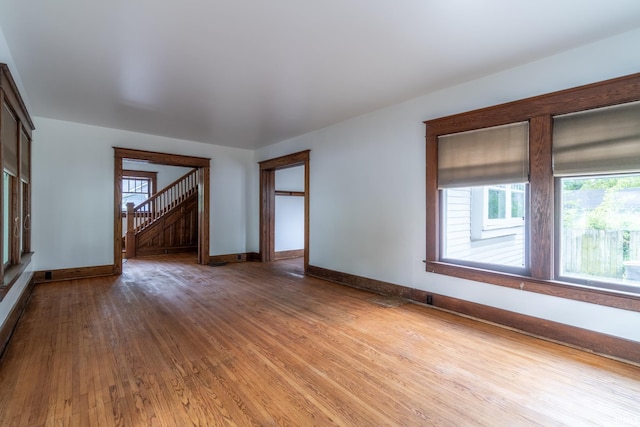 unfurnished room with plenty of natural light, light wood-type flooring, and baseboards