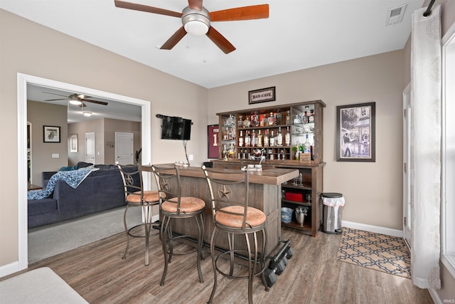 indoor dry bar featuring a ceiling fan, wood finished floors, and baseboards
