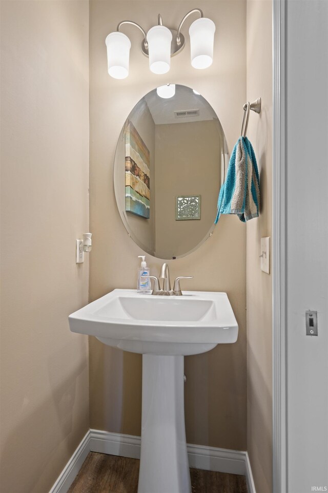 bathroom featuring baseboards, wood finished floors, and a sink
