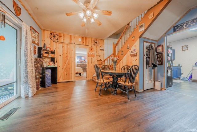 dining area with wood finished floors, plenty of natural light, and wood walls