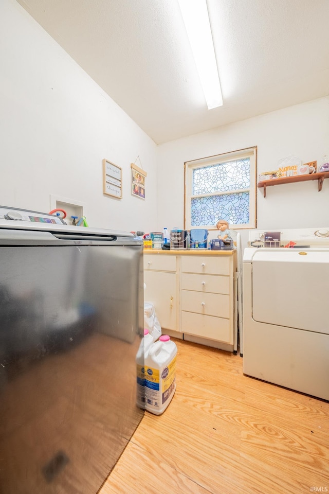 clothes washing area with light wood-style floors and washing machine and clothes dryer