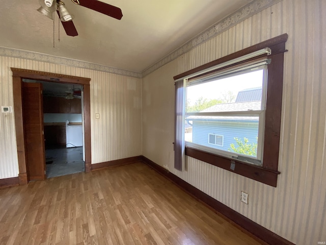 1107 S St, Bedford, IN 47421 - spare room featuring wallpapered walls, ceiling fan, light wood finished floors, and baseboards