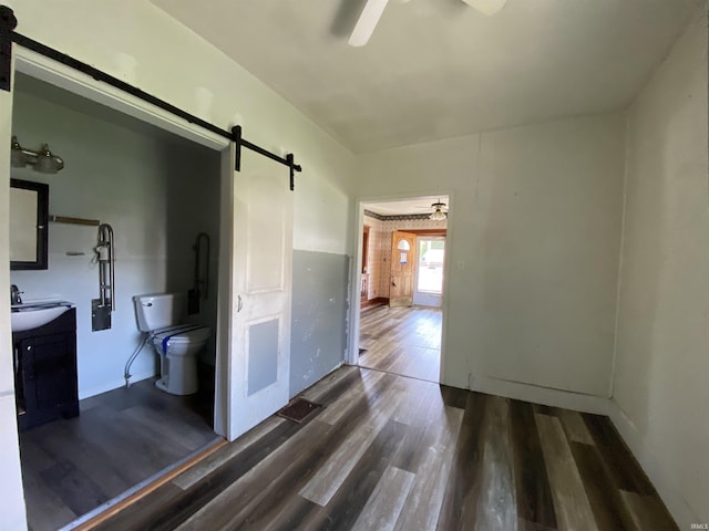 1107 S St, Bedford, IN 47421 - unfurnished bedroom featuring a barn door, dark wood-style floors, ceiling fan, and baseboards