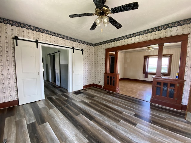 1107 S St, Bedford, IN 47421 - spare room with ceiling fan, a barn door, wallpapered walls, dark wood-type flooring, and baseboards