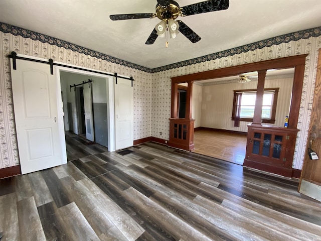 1107 S St, Bedford, IN 47421 - empty room featuring a ceiling fan, a barn door, wood finished floors, baseboards, and wallpapered walls