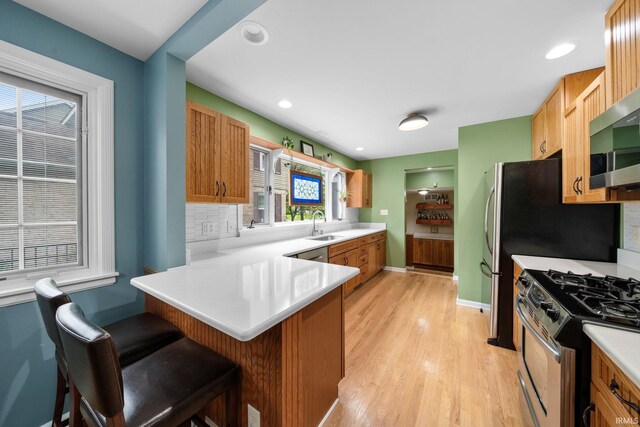 227 N Twyckenham Dr, South Bend, IN 46617 - kitchen with stainless steel appliances, a peninsula, a sink, light wood-type flooring, and a kitchen breakfast bar