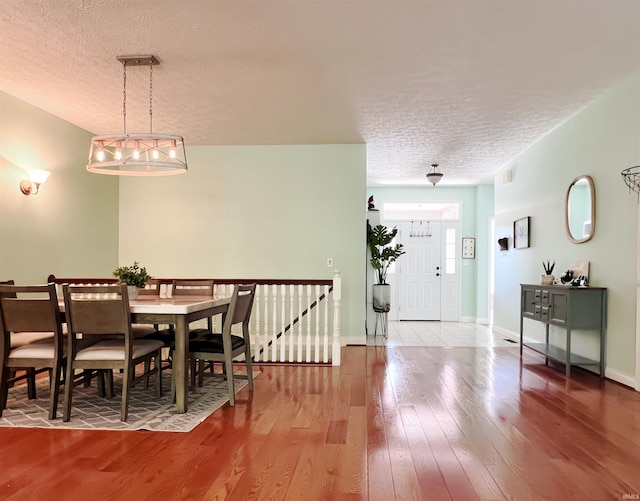 dining room featuring a textured ceiling, hardwood / wood-style floors, and baseboards