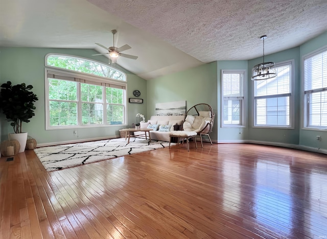 living area with hardwood / wood-style floors, a chandelier, baseboards, vaulted ceiling, and a textured ceiling