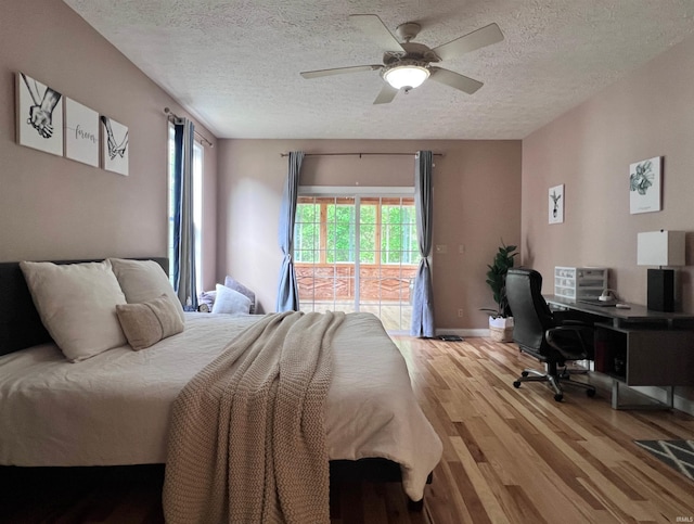 bedroom featuring access to exterior, light wood finished floors, a textured ceiling, multiple windows, and an office area