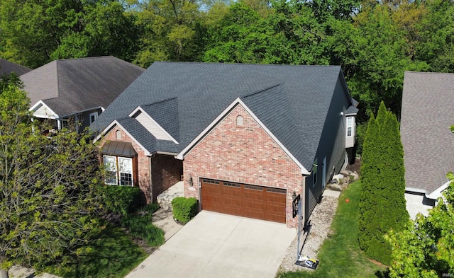 view of front of home with brick siding, a garage, roof with shingles, and driveway