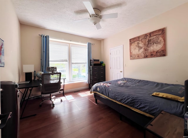 bedroom featuring a textured ceiling, wood finished floors, a desk, and a ceiling fan