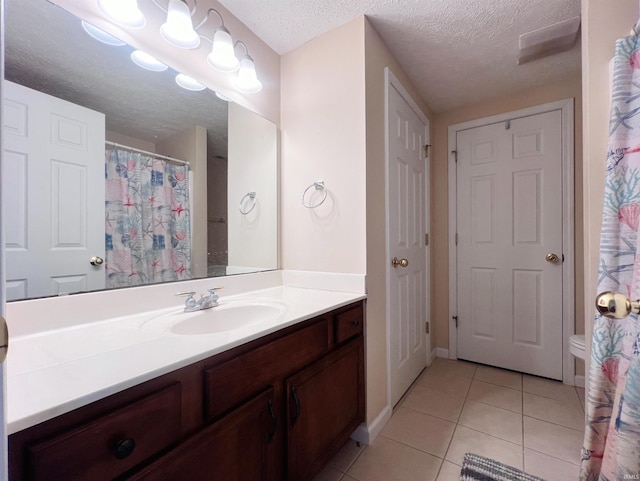 bathroom featuring a textured ceiling, tile patterned floors, vanity, and baseboards
