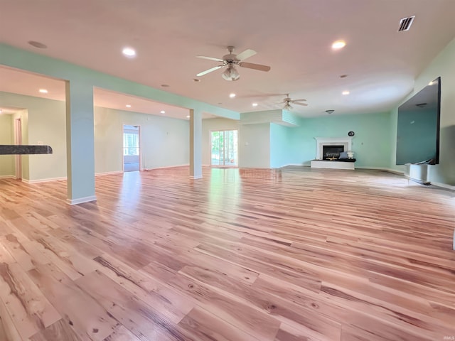 unfurnished living room featuring light wood-style floors, recessed lighting, a fireplace with raised hearth, a ceiling fan, and baseboards