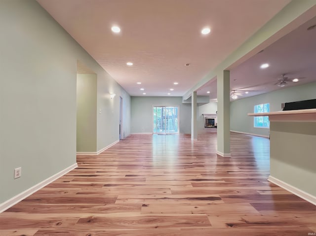 unfurnished living room featuring a glass covered fireplace, wood finished floors, recessed lighting, and a ceiling fan