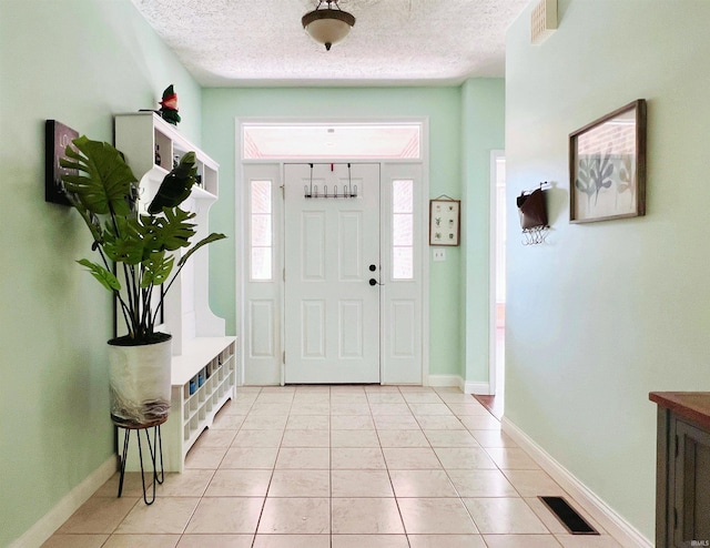 foyer featuring a textured ceiling, light tile patterned flooring, and baseboards