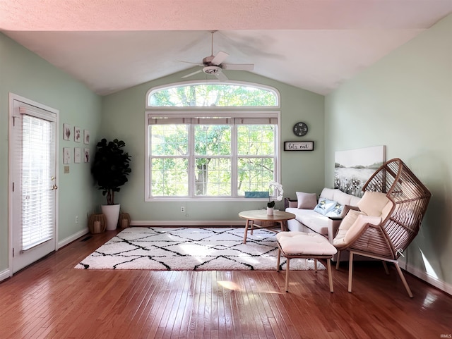 living area featuring a ceiling fan, hardwood / wood-style floors, baseboards, plenty of natural light, and lofted ceiling