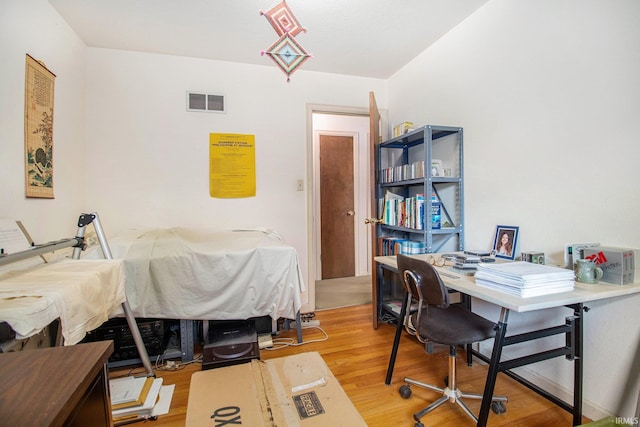 bedroom featuring an office area and light wood finished floors